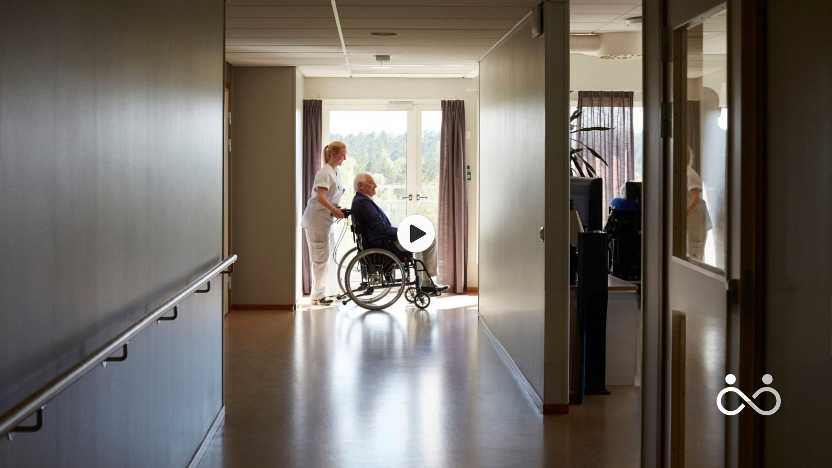 Förhandsbild för Adsuma med omsorgspersonal och en äldre person i rullstol i en ljus korridor